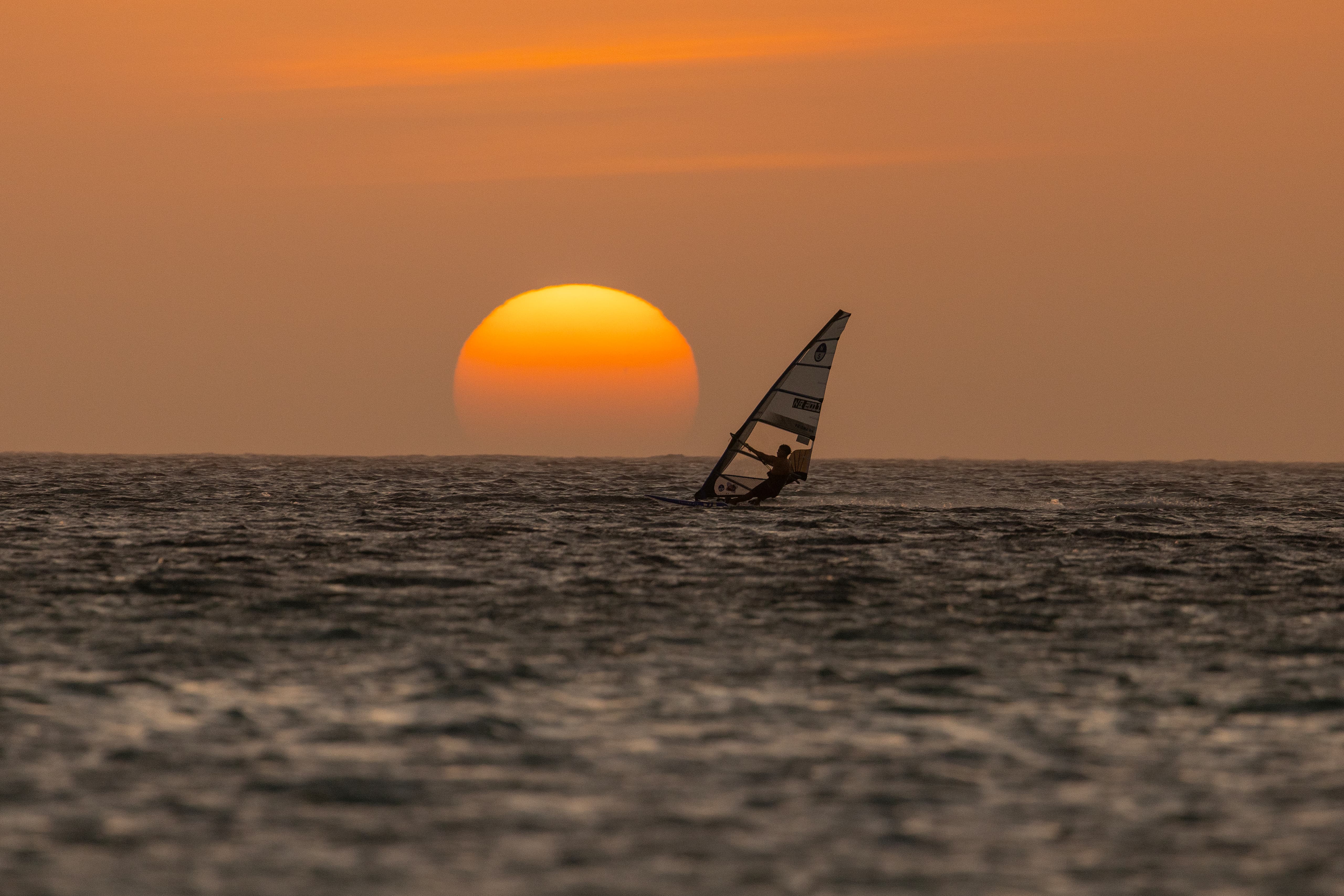Windsurfer sailing toward the sunset